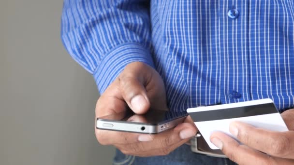 Чоловік тримає кредитну картку і використовує смартфон, концепцію інтернет-покупки — стокове відео