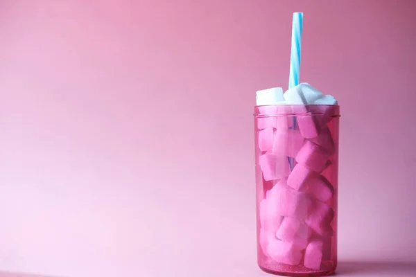 Кубик сахара в пластиковом контейнере на розовом фоне — стоковое фото