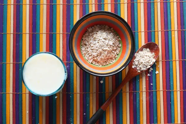 Vista de ángulo alto de copos de avena en un tazón y leche en la mesa — Foto de Stock