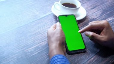 İş adamı eli masada yeşil ekranlı akıllı telefon kullanıyor. 