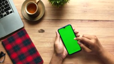 İş adamı eli masada yeşil ekranlı akıllı telefon kullanıyor. 