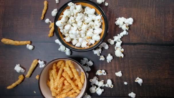 Bovenaanzicht van kom popcorn, chips en TV afstandsbediening op tafel — Stockvideo