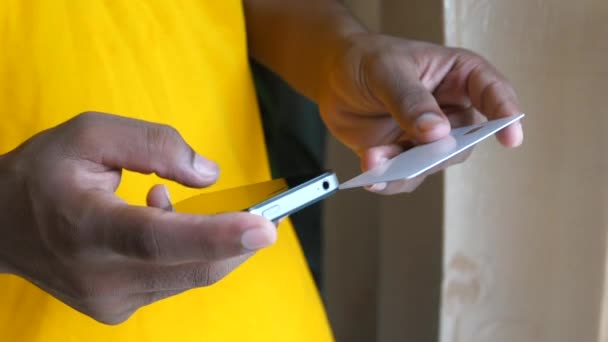 Мужчина держит в руках кредитную карту и пользуется смартфоном для покупок онлайн — стоковое видео