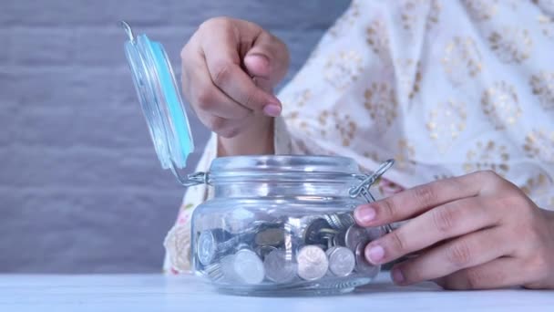 Jóvenes mujeres asiáticas ahorro de monedas en un frasco — Vídeo de stock