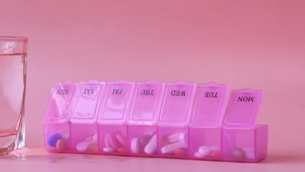 Caja de la píldora y vaso de agua en rosa — Vídeo de stock