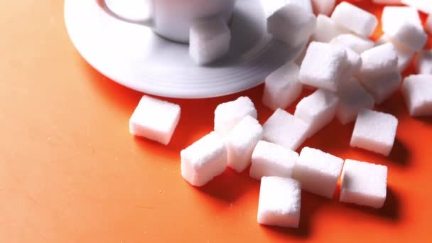 Sucre cube dans une tasse de thé sur fond orange — Video