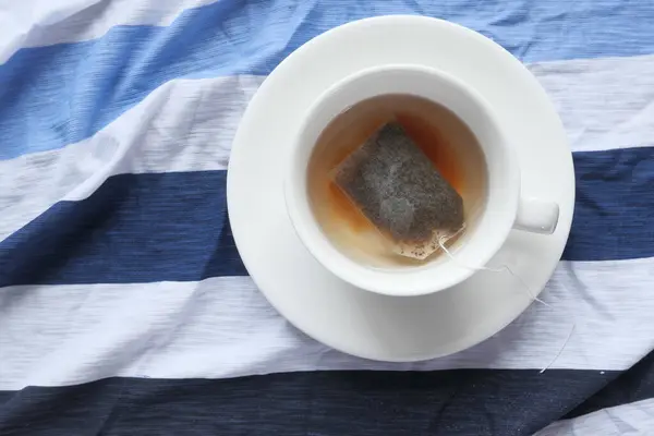 Šálek čaje s čajovým sáčkem na dřevěném stole — Stock fotografie