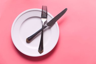 Pembe arka planda temiz tabak ve çatal bıçak takımı