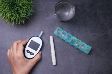 Kadınlar evde diyabetik glikoz seviyesini elle ölçüyorlar. 