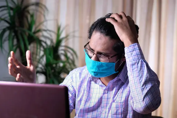 Θλιμμένος άντρας με μάσκα προσώπου που δουλεύει στο λάπτοπ — Φωτογραφία Αρχείου