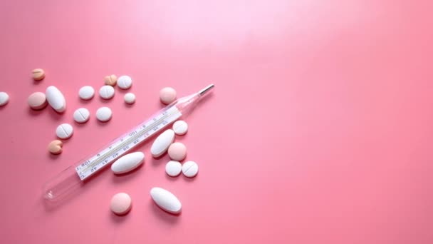 Weiße Pille und Thermometer auf rosa Hintergrund — Stockvideo