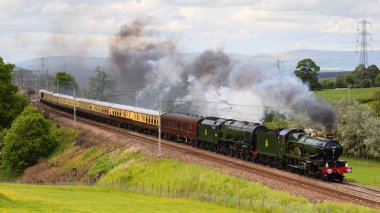 Buhar lokomotifleri 5043 Edgcumbe Dağı Kontu ve 46233 Sutherland Düşesi Kuzey İngiltere 'deki Hackthorpe, Cumbria üzerinden Cumbria Fatihi' nin başına geçtiler..
