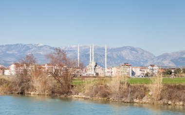 Manavgat Nehri. Manavgat Nehri 'ni geçerek Türkiye' nin güneyindeki Antalya ilinin Manavgat ilçesine doğru bakan manzara. Kulliye Camii, dört minaresi ile ufuk çizgisine hakim..