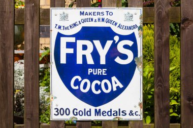 Fry 'ın Saf Kakaosu için eski tarz teneke reklam panosu boyalı ahşap bir arka planda sergileniyor..