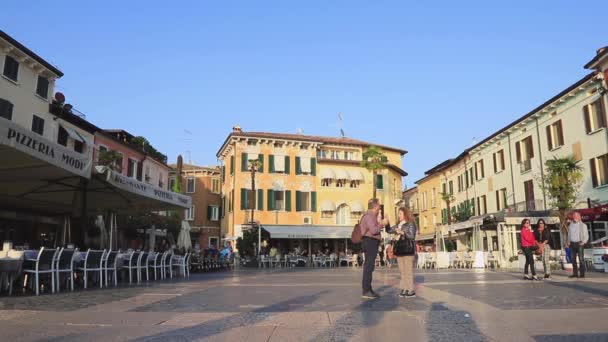 北イタリアのシルミオーネにあるカルドゥッチ広場 観光客や休日のメーカーは シルミオーネのカルッチ広場を横断します シルミオーネは北イタリアのガルダ湖の端にあるリゾートタウンです — ストック動画