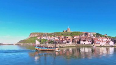 İngiltere 'nin Whitby sahilindeki North Yorkshire kasabasına bir eğlence gemisi geliyor. St. Mary Kilisesi, Doğu Kayalıkları 'nın zirvesinde görülebilir..