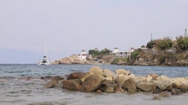 Yunanistan 'ın Mykonos adasındaki kıyı şeridi boyunca uzanan manzara. Arka planda Agios Haralampos kilisesi ve Chlora köyüne bakan geleneksel yel değirmenleri görülebilir..