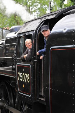 75078 numaralı buharlı trendeki şoför ve itfaiyecinin yakın çekimi. Tren Keighley ve Worth Valley Demiryolu üzerindeki Haworth İstasyonu 'ndan ayrılmaya hazırlanıyor..