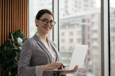 Resmi kıyafetler ve şık gözlüklerle kameraya bakıp gülümseyen başarılı genç müdürün portresi. Bilgisayarı ve interneti kullanan, daktilo eden, modern ofiste çalışan kendine güvenen bir iş kadını.