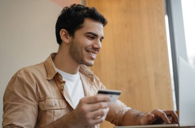 Başarılı bir serbest çalışan ödeme alır. Mutlu Hintli adam dizüstü bilgisayar kullanıyor, kredi kartı tutuyor, internet üzerinden alışveriş yapıyor. Asyalı adam internetten yemek sipariş ediyor, bilet alıyor ve gülümsüyor. 