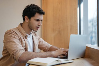 Başarılı Asyalı iş adamı dizüstü bilgisayar kullanıyor, klavyede daktilo kullanıyor, antrenman dersleri izliyor, ofiste planlama yapıyor. Evden çalışan bağımsız Hintli.