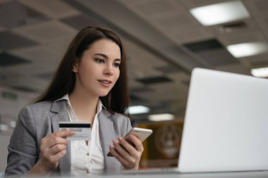 Başarılı bir iş kadını kredi kartı tutuyor, akıllı telefonu online alışveriş için kullanıyor, ofisinde oturuyor. Serbest çalışan ödeme alır, bakiyeyi kontrol eder. İnternetten yemek sipariş eden, bilet alan bir kadın.