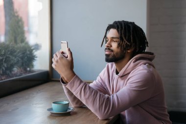 Cep telefonu, iletişim, kafede oturan yakışıklı Afro-Amerikan adam. Evde başarılı bir serbest çalışan.