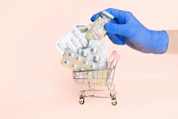 hand in medical gloves put bottle with capsule to shopping cart with medicine pills isolated. online order pharmacy delivery. safe courier delivery medicine. pharmaceutical business. mock up template.