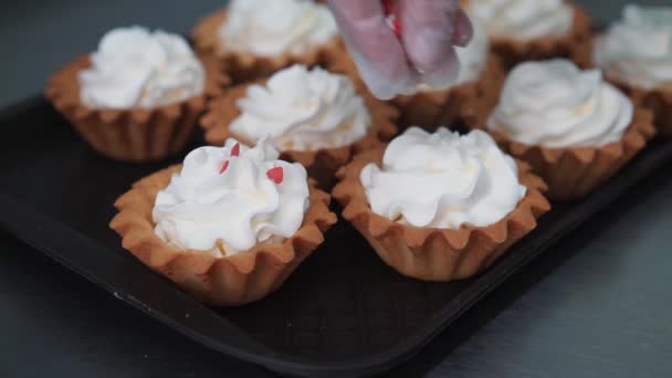 女性の手のパーティーショットのためのマルチカラーカップケーキを作る調理バッグ菓子を使用してクリームとカップケーキを飾るおいしいケーキの上にバタークリームを置くホームベーカリーコンセプト — ストック動画