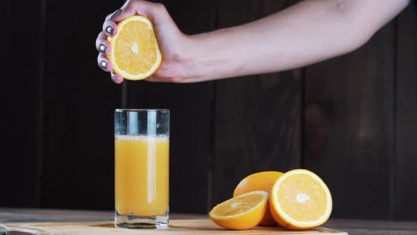 グラスの中で絞りたてのオレンジジュースが木の背景に絞りオレンジジュースを注ぐ — ストック動画