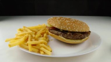 Hamburger, kızarmış patates cipsinin üzerine düşüyor ağır çekimde fast food abur cubur konsepti