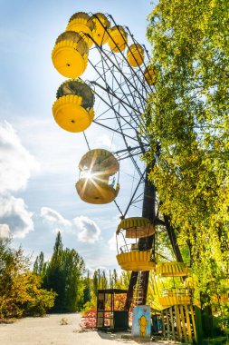 1970 'lerdeki terk edilmiş Pripyat kasabasında kullanılmayan dönme dolap. Hiç kimse. Arka planda güneş ışığı ve sonbahar doğası olan dikey bir fotoğraf. 2019.10.08