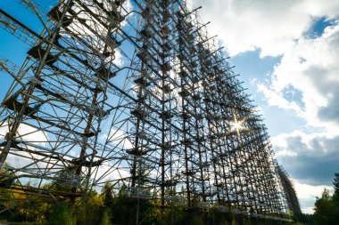 Ufuk ötesindeki Sovyet Radar Ağı Metal Yapısı Çernobil Yasaklama Bölgesi 'nde. Radarın arkasında güneş parlaması olan dikey görüntü. Arkaplan resmi. 2019.10.08.