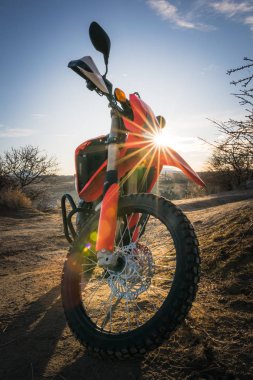 Kapadokya 'nın Goreme kasabasının önünde güneş doğarken kırmızı serin çapraz yarış motosikleti duruyor. Arka plan dikey fotoğrafı. 2019.12.15.