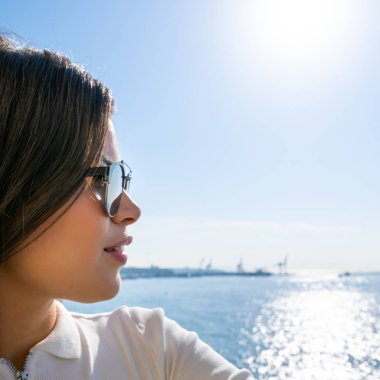 Close headshot of pretty female face. Girl with sunglasses and  sexy lips is looking to the sea. Blank space image.