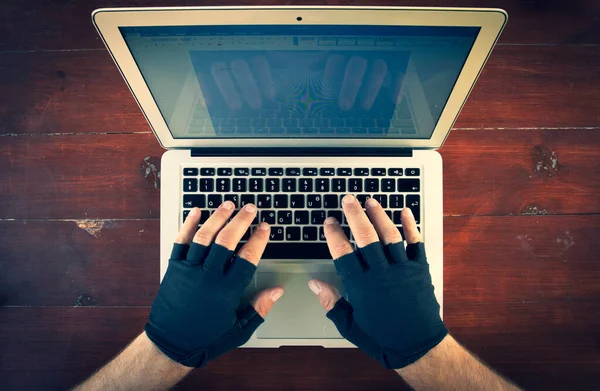 look down to the males hands with gloves typing on laptop keyboard on the red wood background. Background of working space.