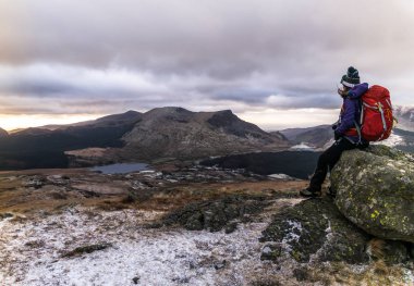 Kişi oturuyor ve dağlara bakıyor.