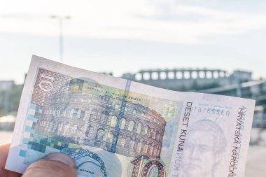 Hırvat on Kuna 'nın kağıt defteri Craotia' daki tarihi Pula arenasının önünde bir elde tutuluyor. 2020 Turizm ve Hırvat vergileri.