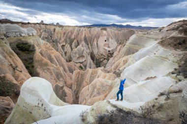 Elleri açık maceraperest bir insan kayanın üzerinde duruyor ve Kapadokya 'nın manzarasının tadını çıkarıyor. Türkiye 'de seyahat hedefi.