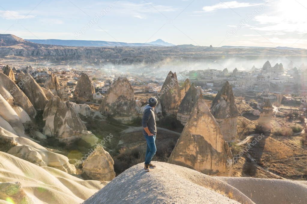 Male person is looking over the shoulder thinking and enjoying fresh morning views in Cappadocia surounded by fairy chimneys. and rocky landscape. Concept of new life  beginning. Goreme.Turkey.