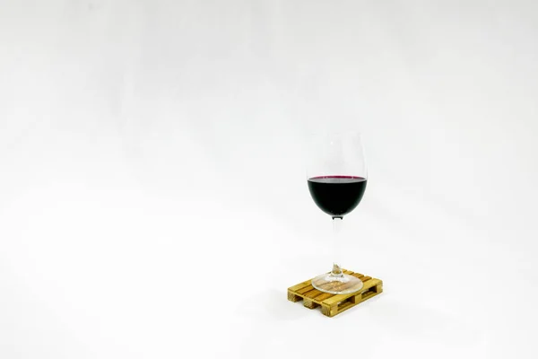 Glass of wine sits on the pallete in white background. Blank space image. Deliveries and trasnportation of wine.