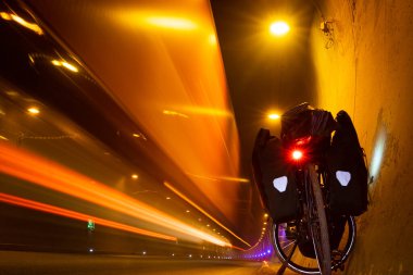 Tur bisikleti, tünelin içinde yanından geçen arabalarla duruyor. Güvenlik ve bisiklet yolculuğunun tehlikeleri. Siyah beyaz arkaplan.