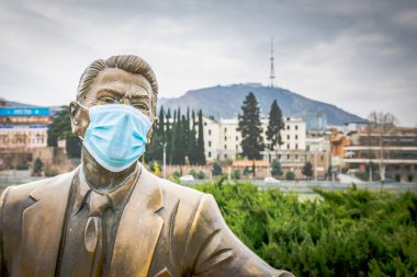 Rike Park 'taki Ronald Reagan heykelinin arkasında maske ve Tiflis TV kulesi var. Tiflis 'te salgın. Georgia. 25.03.2020.