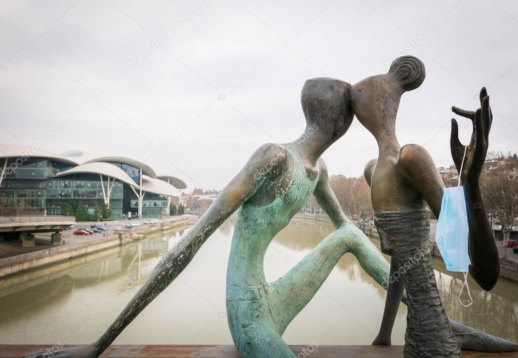 Statue of a couple with medical mask on Baratashvili bridge.Concept of relationship during quarantine and pandemic of corona virus. Tbilisi.Georgia 23.03.2020.