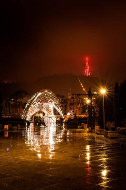 Geceleyin Rike Park yolu üzerinde barış köprüsü ve arka planda ışık saçan televizyon kulesi var. Tiflis. Georgia mı? 25.03.2020