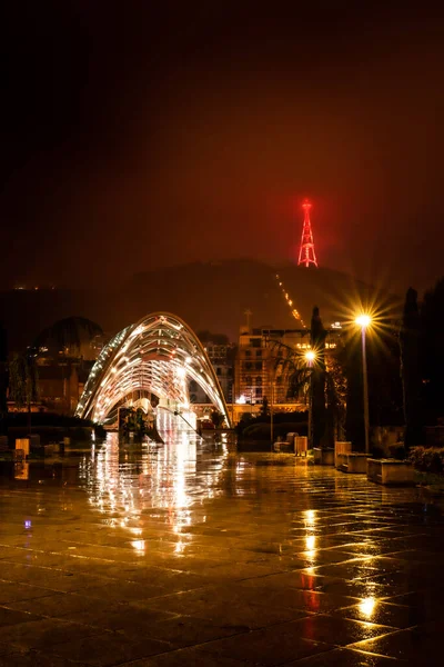 Geceleyin Rike Park yolu üzerinde barış köprüsü ve arka planda ışık saçan televizyon kulesi var. Tiflis. Georgia mı? 25.03.2020