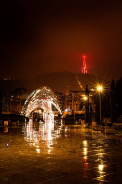 Geceleyin Rike Park yolu üzerinde barış köprüsü ve arka planda ışık saçan televizyon kulesi var. Tiflis. Georgia mı? 25.03.2020