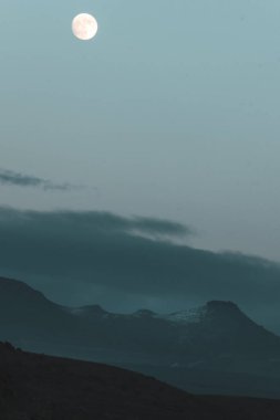 Dolunay, dağ zirvesi ve bulutlu gökyüzü ile dikey görüntü. Karmaşık dramatik astro fotoğrafları.