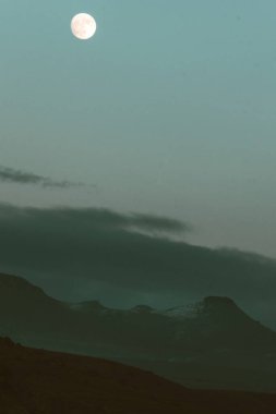 Dolunay, dağ zirvesi ve bulutlu gökyüzü ile dikey görüntü. Karmaşık dramatik astro fotoğrafları.