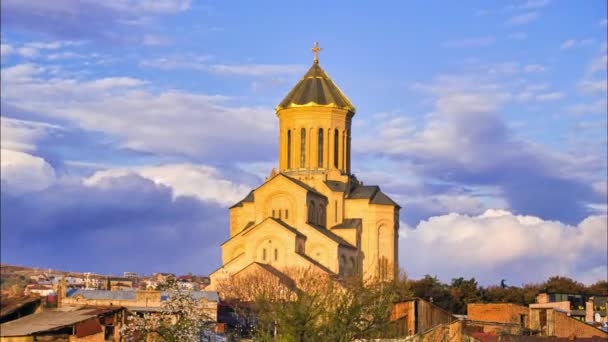 Orthdodox Dreifaltigkeitskirche in Tiflis mit den Dächern der Häuser ringsum und blühenden Frühlingsbäumen. Religion und Kultur der Kartwelier. Dramatischer Zeitraffer. Sakartwelo. — Stockvideo